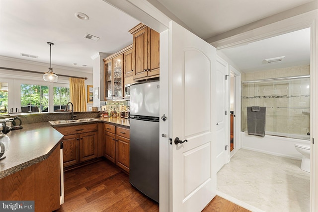 kitchen featuring sink, stainless steel refrigerator, dark hardwood / wood-style floors, decorative light fixtures, and kitchen peninsula