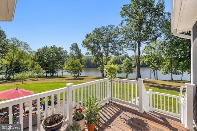 wooden terrace with a water view and a lawn