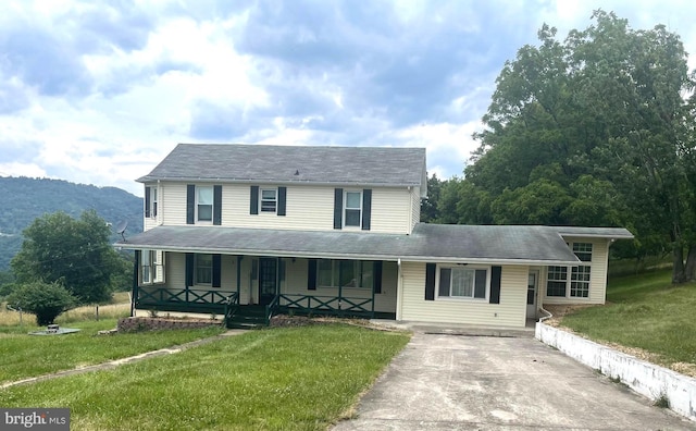 view of front of property featuring covered porch, a front lawn, and a mountain view