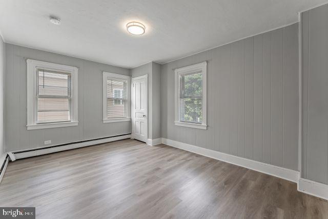 unfurnished bedroom with a baseboard radiator and light hardwood / wood-style flooring