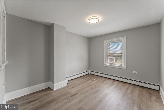 empty room with light hardwood / wood-style floors and baseboard heating