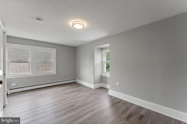 empty room featuring hardwood / wood-style floors and a baseboard radiator