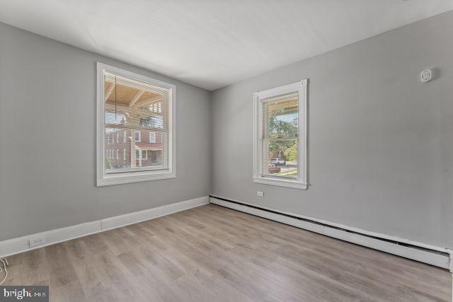 empty room featuring a wealth of natural light, light hardwood / wood-style flooring, and baseboard heating