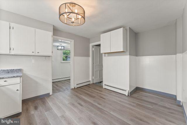 kitchen featuring white cabinets, baseboard heating, and light hardwood / wood-style flooring