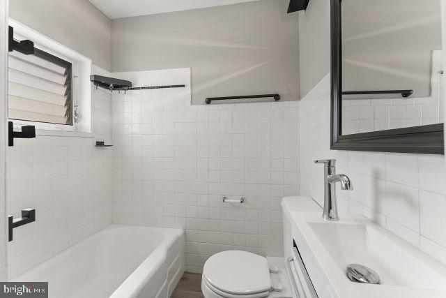 full bathroom with  shower combination, vanity, tile walls, and toilet