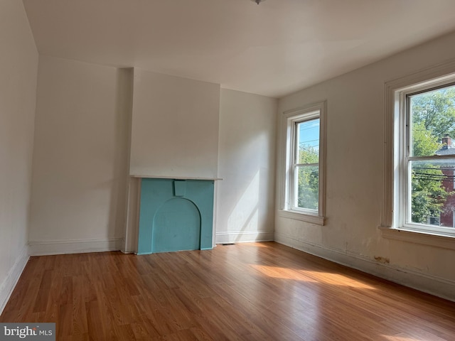 unfurnished living room with light wood-style floors, plenty of natural light, and baseboards