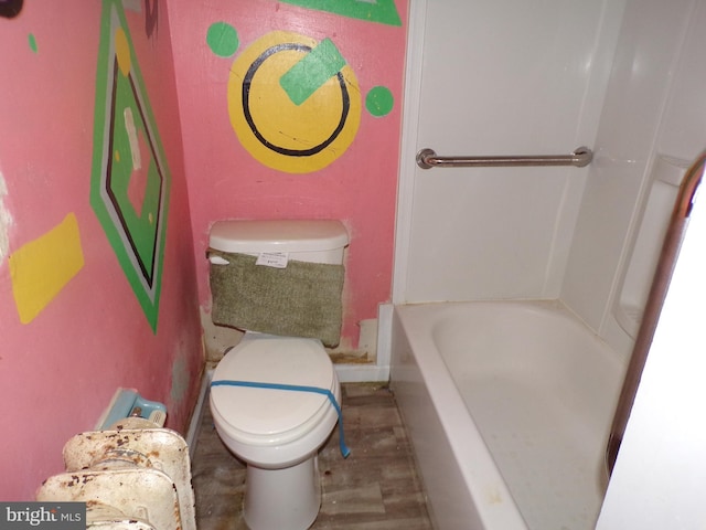 bathroom featuring toilet, wood-type flooring, and a tub