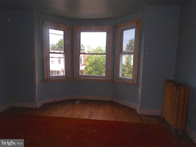 empty room featuring radiator heating unit and hardwood / wood-style flooring