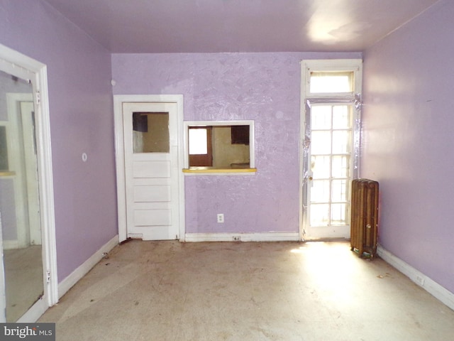 unfurnished room featuring plenty of natural light and radiator