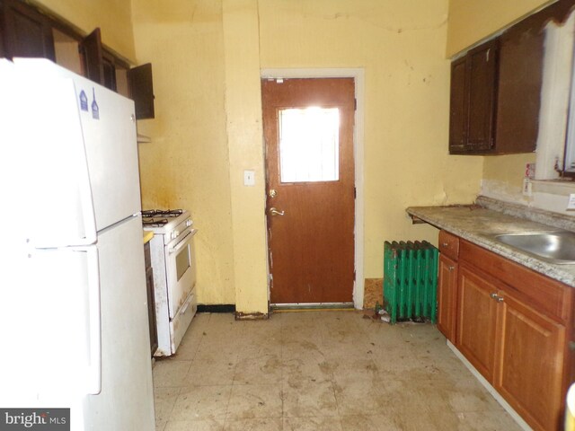 kitchen with white appliances, radiator, and sink