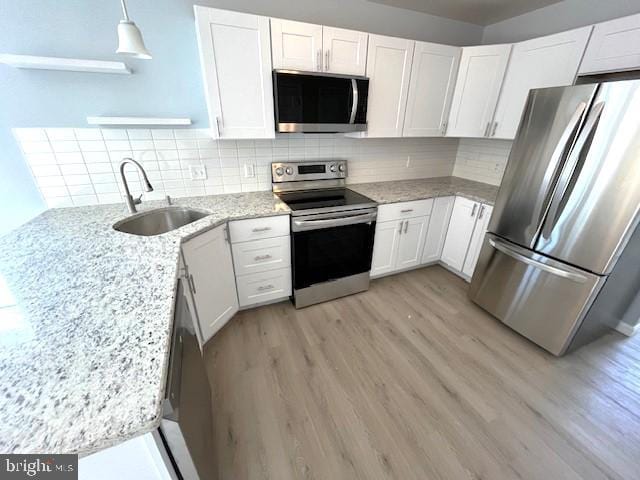 kitchen featuring white cabinetry, appliances with stainless steel finishes, sink, and pendant lighting