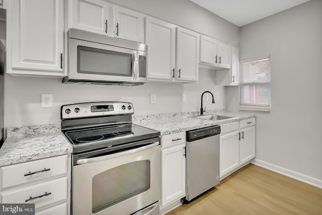 kitchen with stainless steel appliances, light hardwood / wood-style flooring, white cabinetry, sink, and light stone countertops