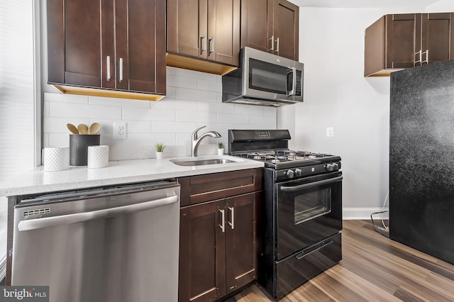 kitchen featuring backsplash, black appliances, sink, light wood-type flooring, and dark brown cabinets