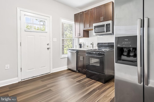 kitchen with dark brown cabinets, dark hardwood / wood-style floors, decorative backsplash, and appliances with stainless steel finishes