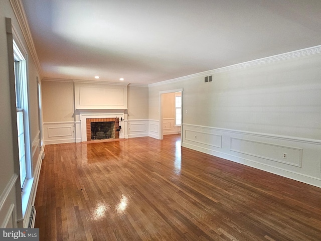 unfurnished living room featuring hardwood / wood-style flooring, ornamental molding, and a brick fireplace