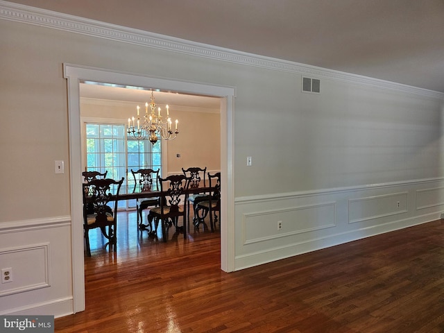 dining area with a notable chandelier, ornamental molding, and dark hardwood / wood-style flooring