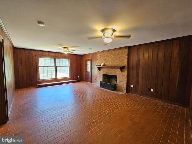 unfurnished living room with crown molding, wood walls, and ceiling fan