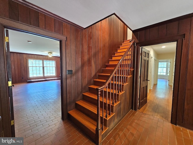 stairway with a healthy amount of sunlight, wood-type flooring, and wood walls