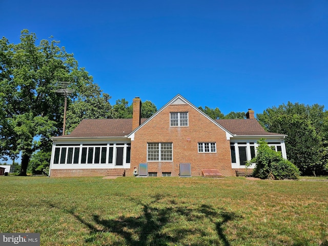 rear view of property with a yard, central air condition unit, and a sunroom