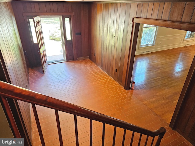 foyer with wooden walls and wood-type flooring