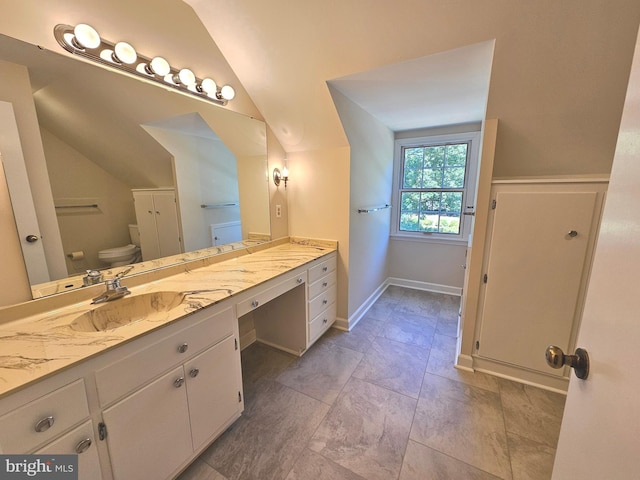 bathroom featuring toilet, vanity, and vaulted ceiling