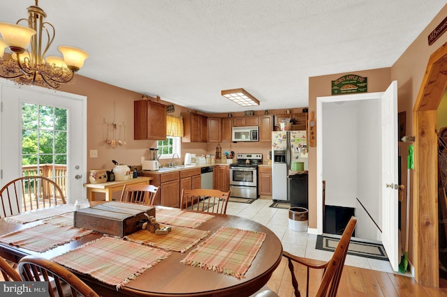 dining space with sink, a textured ceiling, and an inviting chandelier