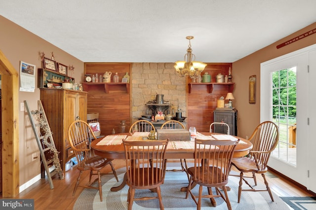 dining area featuring a textured ceiling, light hardwood / wood-style flooring, a wood stove, and a notable chandelier