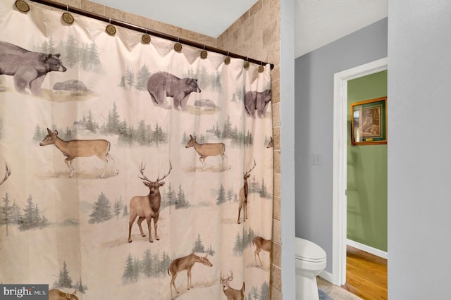 bathroom with a shower with shower curtain, hardwood / wood-style floors, and toilet