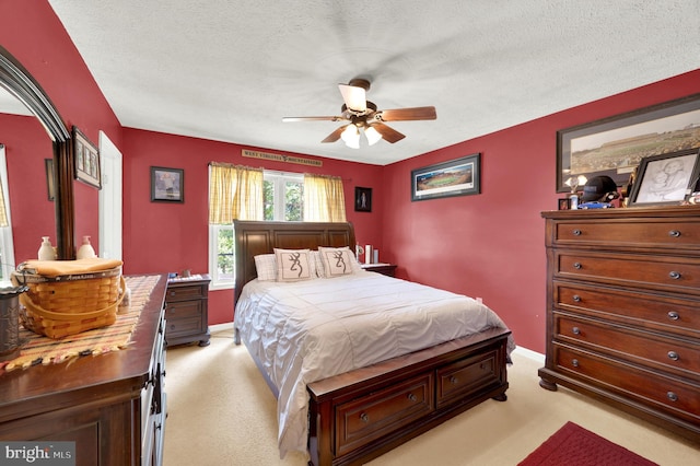 bedroom featuring ceiling fan, light colored carpet, and a textured ceiling