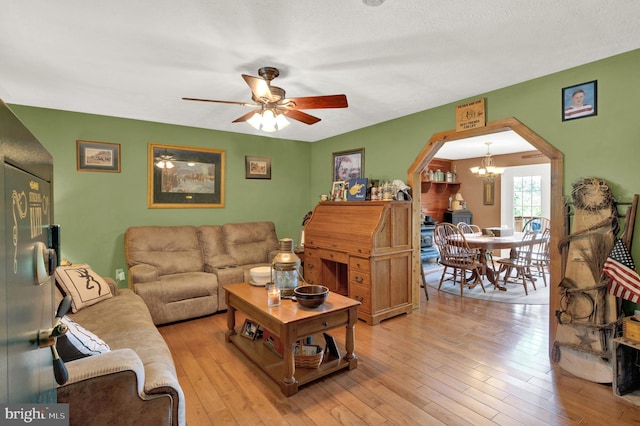 living room with a textured ceiling, light hardwood / wood-style flooring, and ceiling fan with notable chandelier