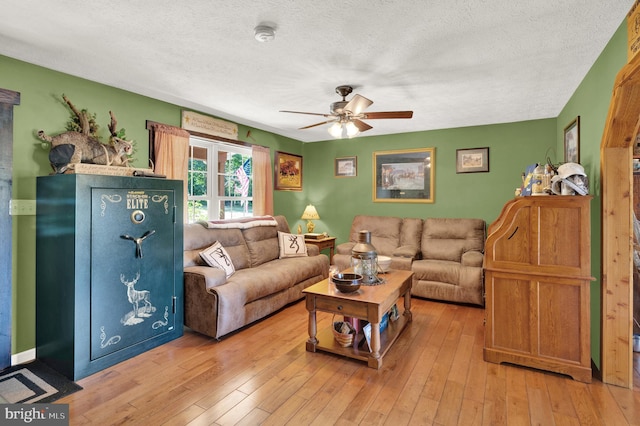 living room with ceiling fan, light hardwood / wood-style floors, and a textured ceiling