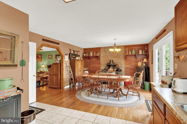 dining space featuring built in shelves, a wood stove, light wood-type flooring, and an inviting chandelier