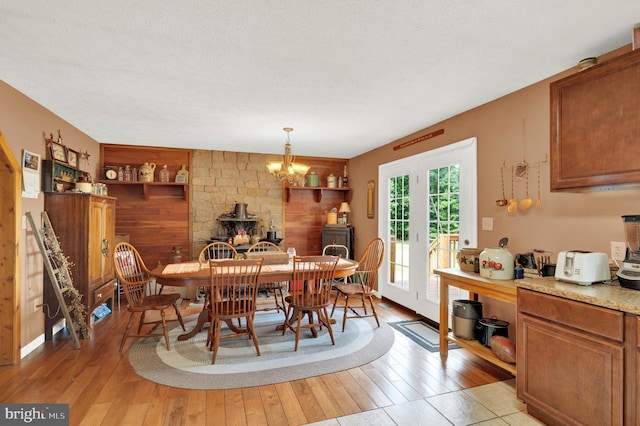 dining area with a wood stove, french doors, built in shelves, light wood-type flooring, and a textured ceiling