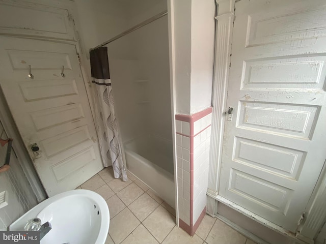 bathroom with tile patterned flooring, shower / bath combo with shower curtain, and sink