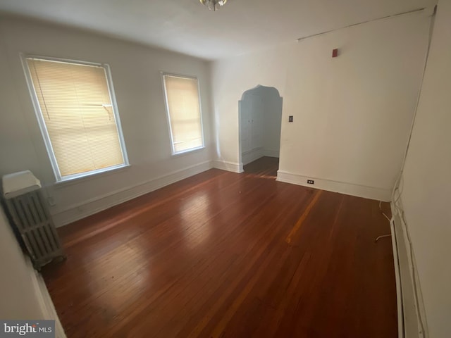 spare room with dark hardwood / wood-style flooring and radiator