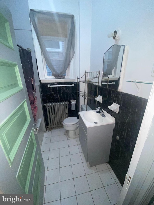 full bathroom featuring vanity, radiator, tile patterned floors, toilet, and tile walls