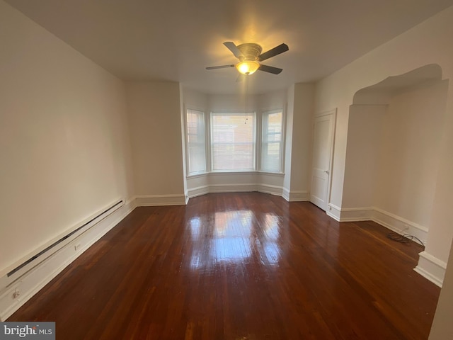 empty room with dark hardwood / wood-style flooring, baseboard heating, and ceiling fan