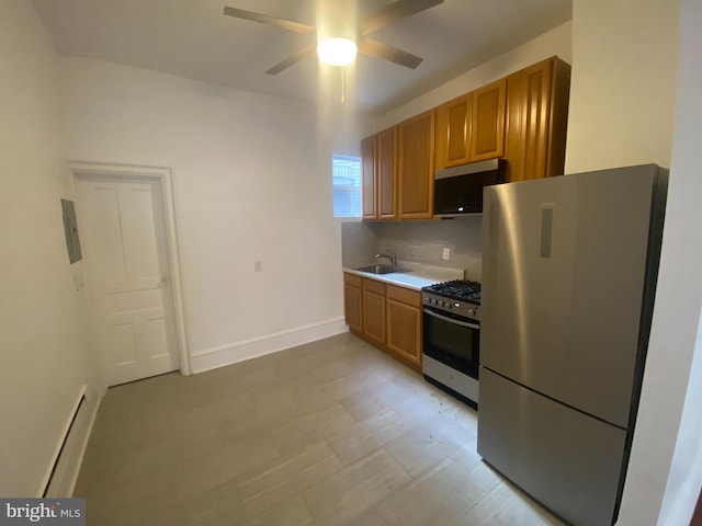 kitchen featuring ceiling fan, sink, a baseboard heating unit, decorative backsplash, and appliances with stainless steel finishes