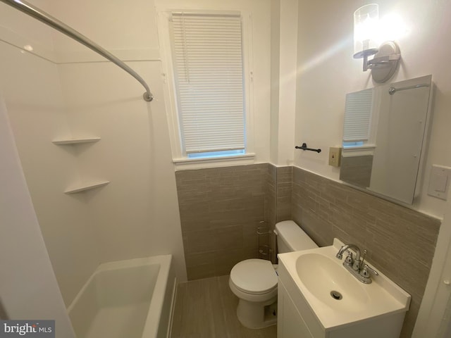 bathroom with vanity, toilet, tile walls, and walk in shower