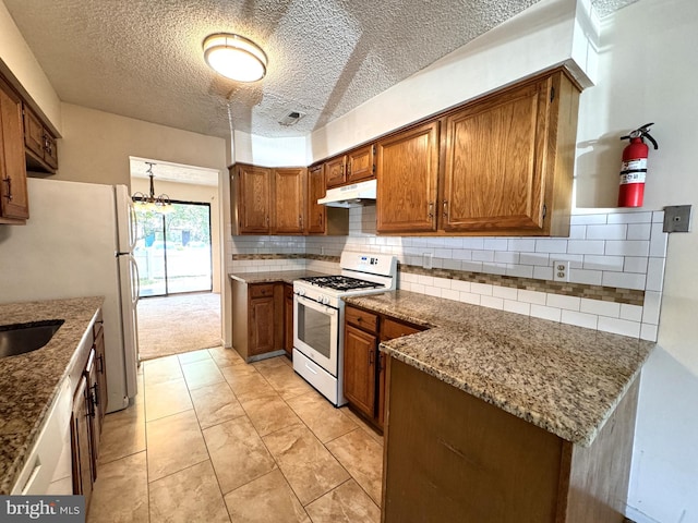 kitchen with white appliances, an inviting chandelier, a textured ceiling, tasteful backsplash, and light stone counters