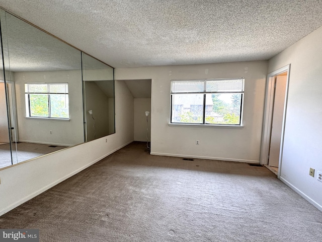 unfurnished room with carpet and a textured ceiling