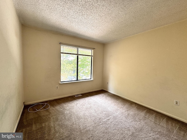 empty room featuring dark carpet and a textured ceiling