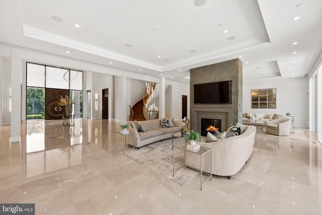 living room featuring a large fireplace and a tray ceiling