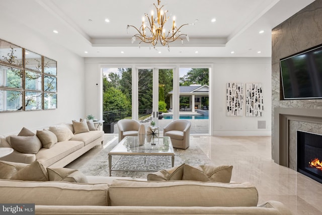 living room featuring a tray ceiling, french doors, a high end fireplace, and a chandelier