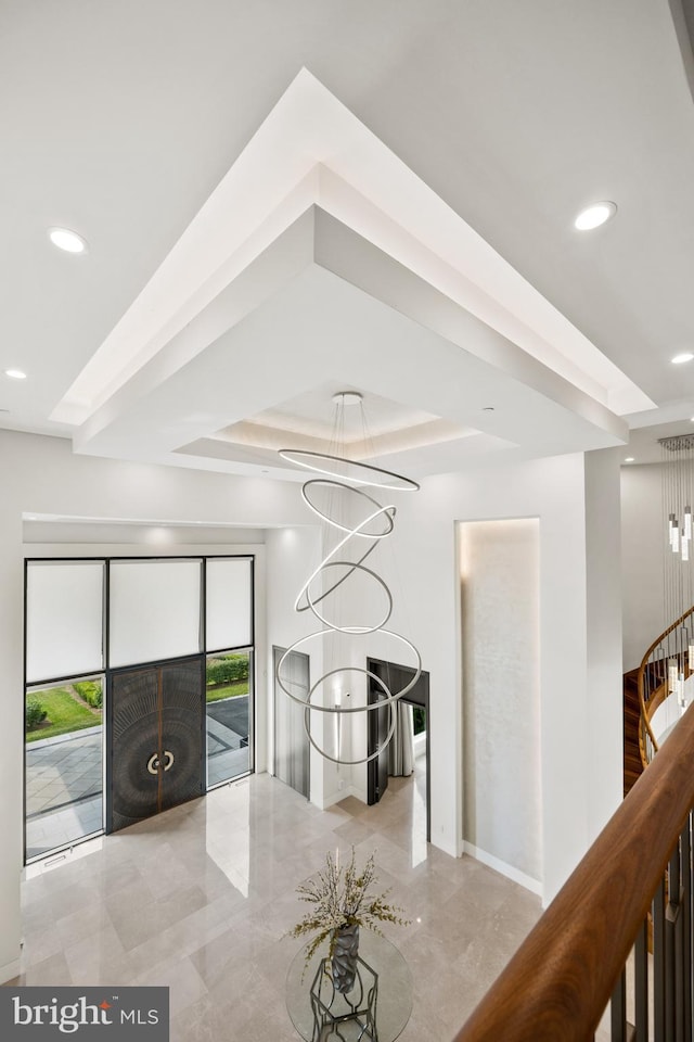 interior space with a raised ceiling and a chandelier