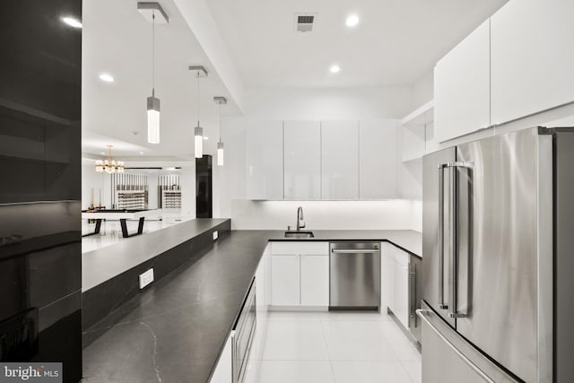 kitchen featuring kitchen peninsula, stainless steel appliances, light tile patterned floors, white cabinetry, and hanging light fixtures