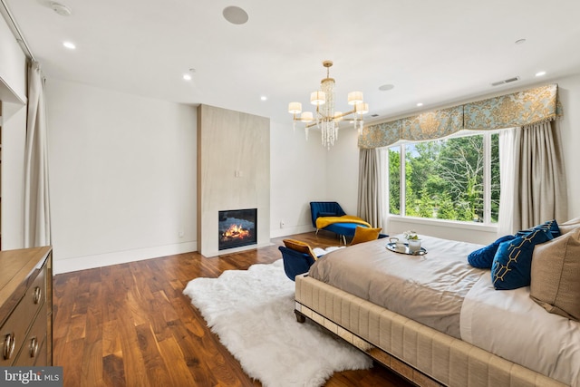 bedroom featuring a notable chandelier, dark hardwood / wood-style floors, and a fireplace