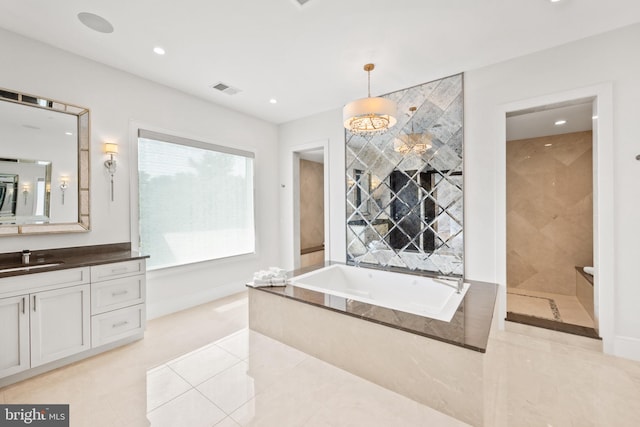 bathroom featuring tile patterned flooring, vanity, and tiled bath