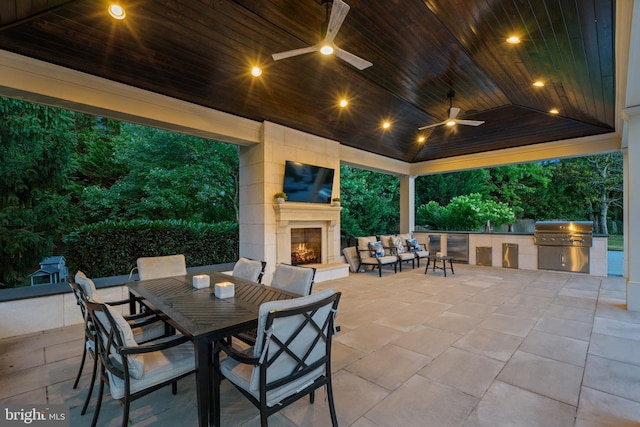 view of patio featuring exterior fireplace, grilling area, ceiling fan, and exterior kitchen