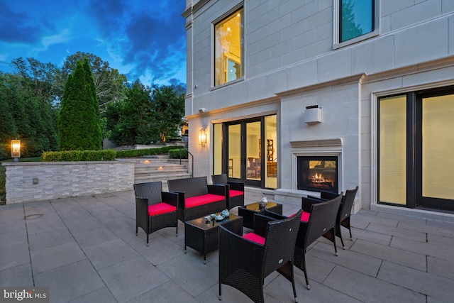 patio terrace at dusk with an outdoor living space with a fireplace